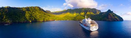 Das Postschiff Aranui 5 vor den grünen hügeligen Küste der Südseeinsel Tahuata, Französisch-Polynesien