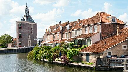 [Translate to Slowtravel experience:] Sailing by historic houses by the water in Enkhuizen, Netherlands