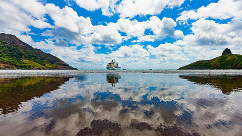 Das Schiff Aranui 5 vor einem Südsee Panorama der Marquesas Insel Hiva Oa mit Meer und grünen Hügeln 
