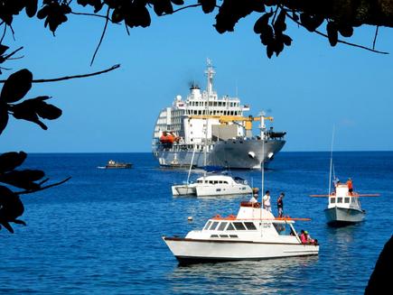 The ship Aranui 5 in front of a South Sea panorama of the Marquesas island Tahuata with ocean and clear blue sky