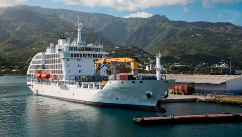 The mail ship Aranui 5 in front of a South Seas panorama of the Marquesas Island in French Polynesia with sea and green hills 