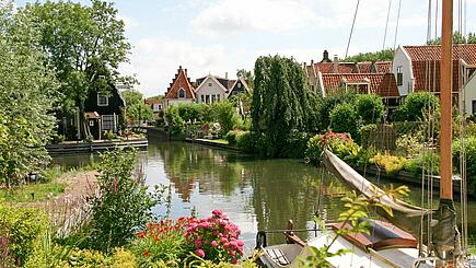 Üppige grüne Gärten und Häuser an der Gracht in Edam, auf Rad- und Segelreise in Holland/ Niederlande