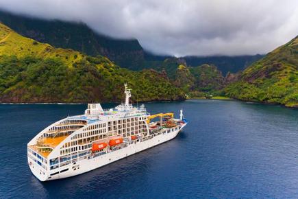 The mail ship Aranui 5 in front of a South Seas panorama of the Marquesas island Fatuiva in French Polynesia with sea and green hills 