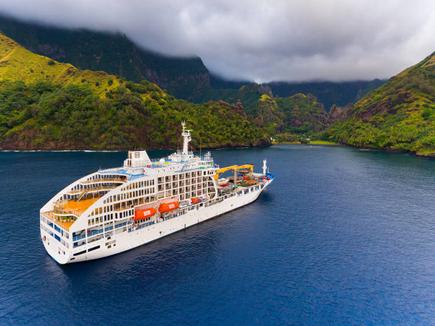 Das Postschiff Aranui 5 vor einem Südsee Panorama der Marquesas Insel Fatuiva in Französisch-Polynesien mit Meer und grünen Hügeln 
