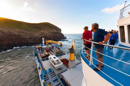 Passengers of the cargo ship Aranui 5 look from the deck to the cliffs of the South Sea island Ua Huka