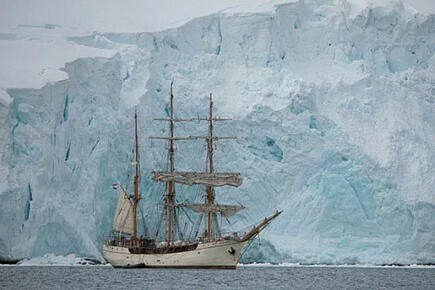 Sailing ship Bark Europa in front of glaciers on trip to Antarctica