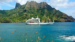 Das Postschiff Aranui 5 vor einem Südsee Panorama der Marquesas Inseln mit Meer und grünen Hügeln 