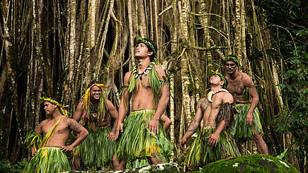 Marquesas dancer in folklore dress against dense jungle background, French Polynesia