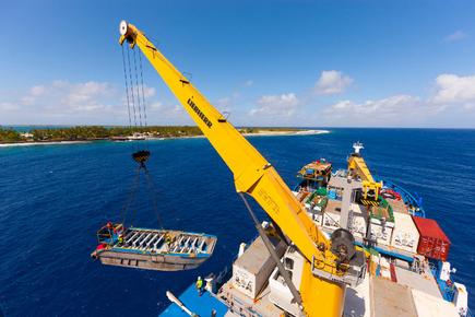 The pontoon of the cargo ship Aranui 5 is lowered into the water by crane off the South Sea island of Takapoto